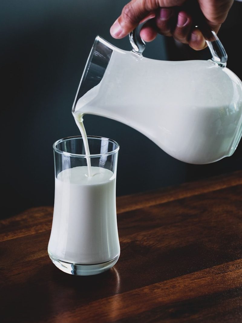 person pours milk into glass